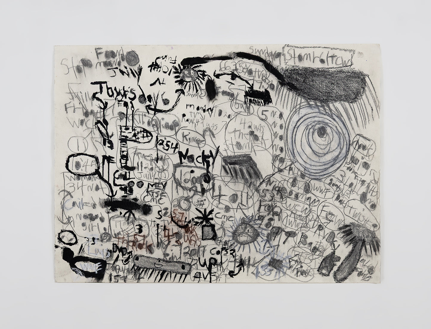 A work on paper made with charcoal and pencil and ink, photographed on a white wall. The surface is covered with a dense pattern of text and symbols. The imagery is built up in layers, and features arrows, suns, storm clouds, and handwritten text referring to weather, time, wrestlers, and movies.