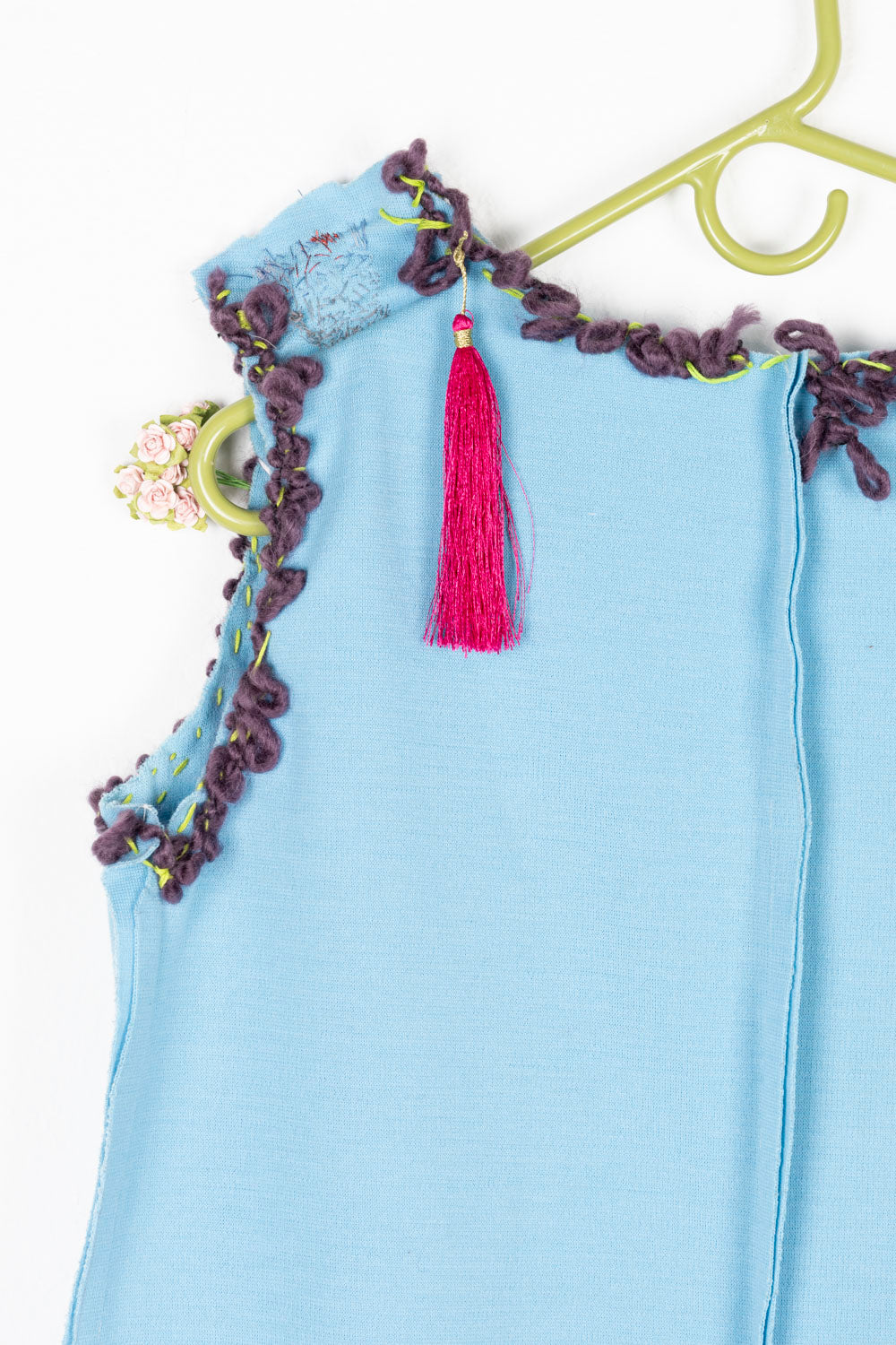 This is a light blue dress with purple embroidery on the collar and the arm holes. There is also a pink tassel on the back left shoulder.