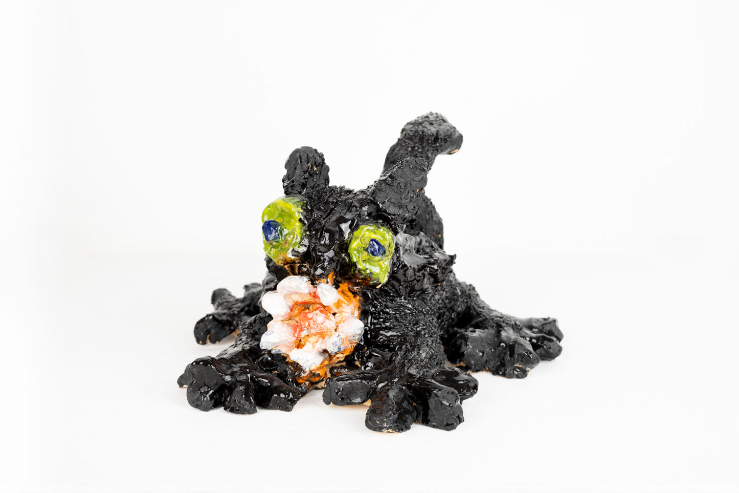Black ceramic cat figurine with colorful eyes against a white background.