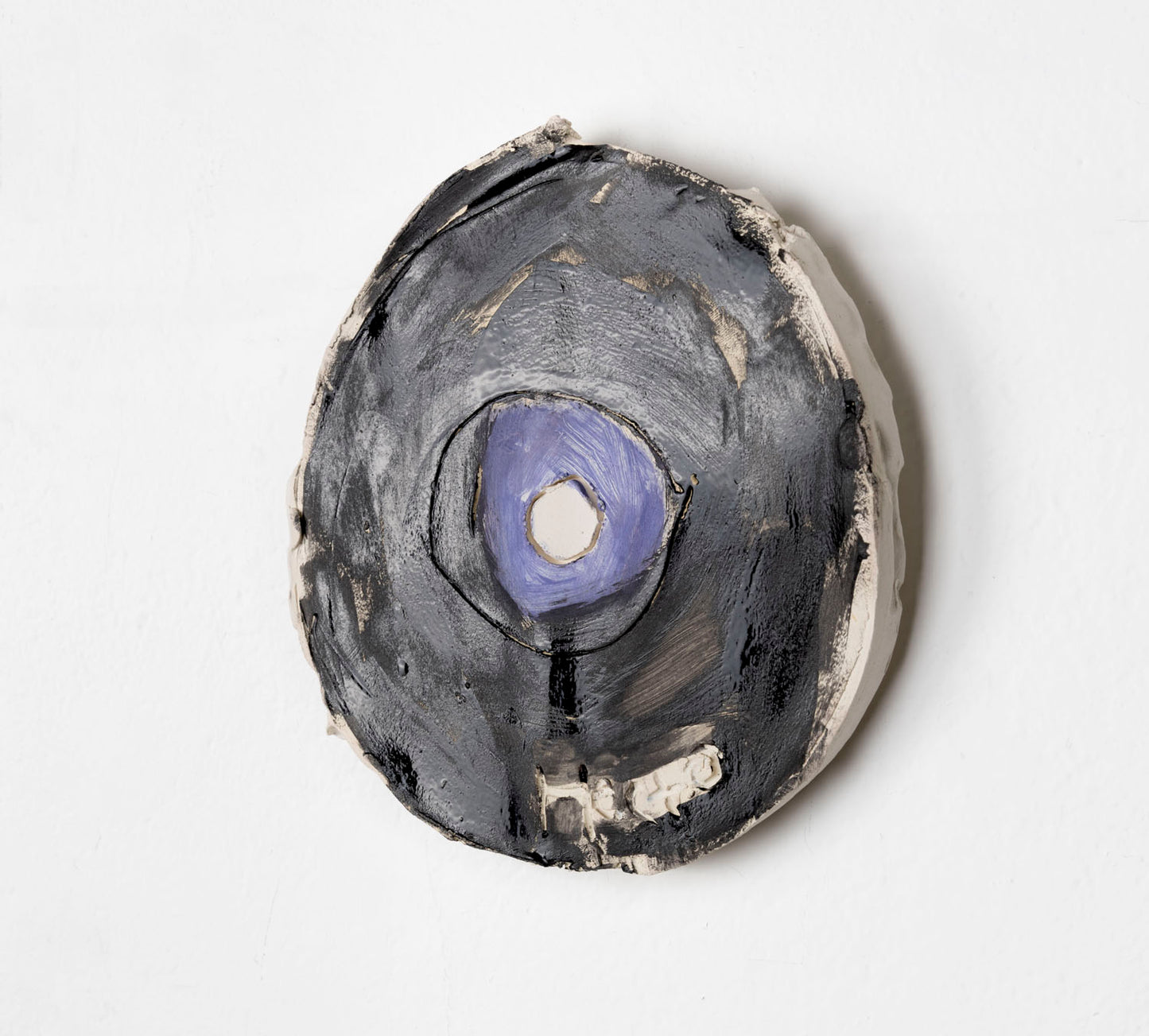 This is a ceramic sculpture of a record, the majority of the record is glazed in black, with a purple glaze for the center.