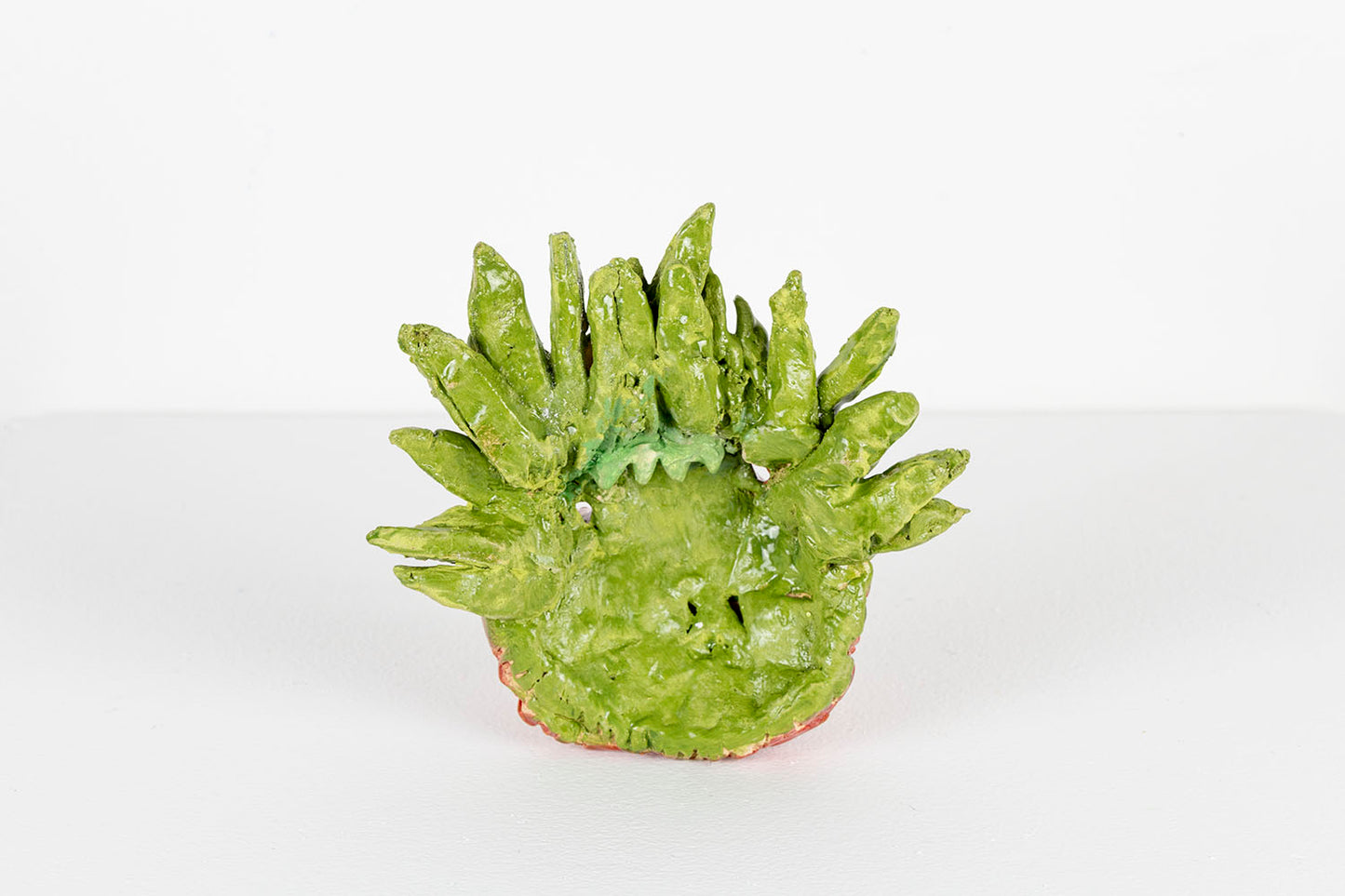 The same mask photographed from the back. This side of the object is glazed all light green, like the crown of leaves.