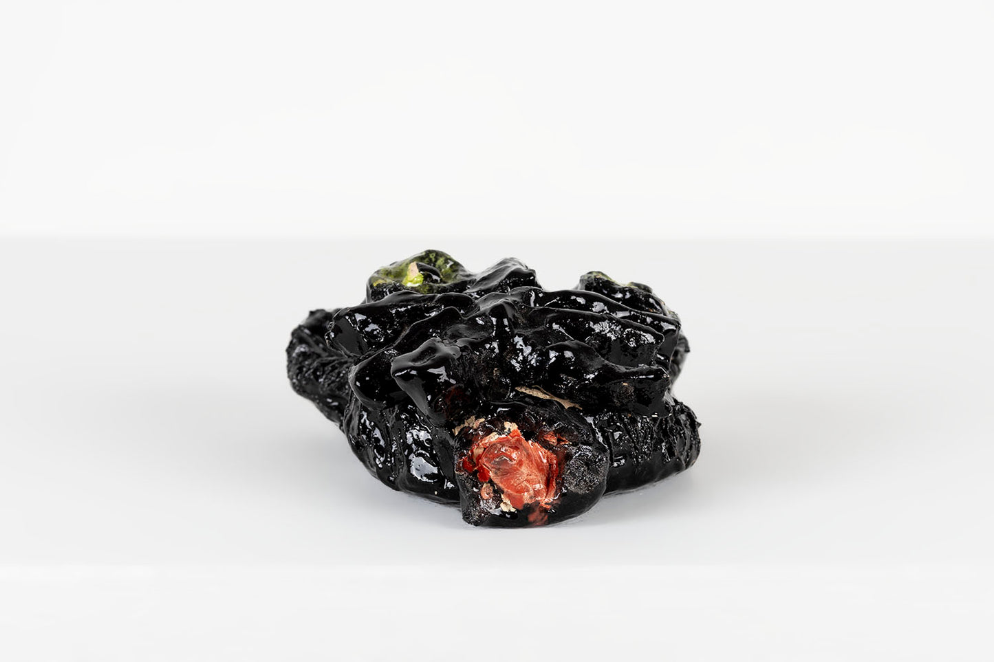 The black cat mask photographed from a low angle to show its dimension. The mask is rather slim, and lies flat against the wall. The whiskers are thick raised bars that extend across the cat's cheeks.