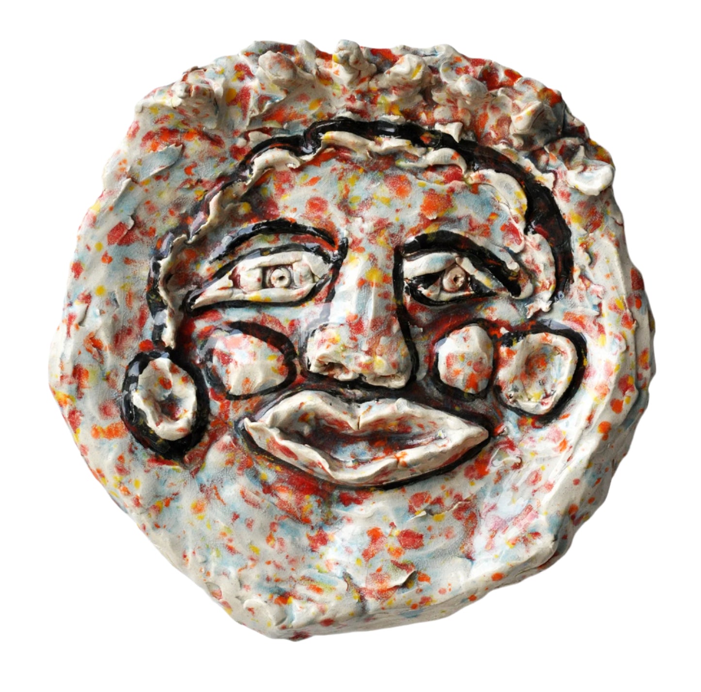 A face with features outlined in black glaze. The background glaze colors look like bright scattered confetti in tones of red, yellow, orange, and blue.