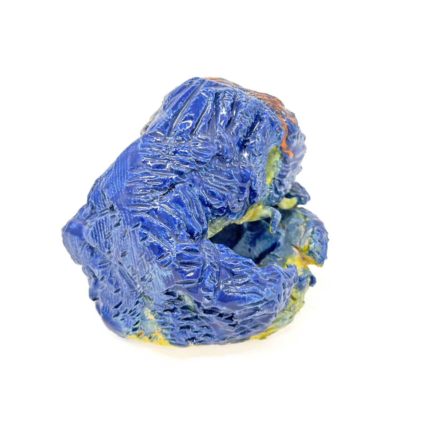 The same sculpture photographed from the side. The glaze has a glossy quality and so the blue paint reflects the light of the white space around it.