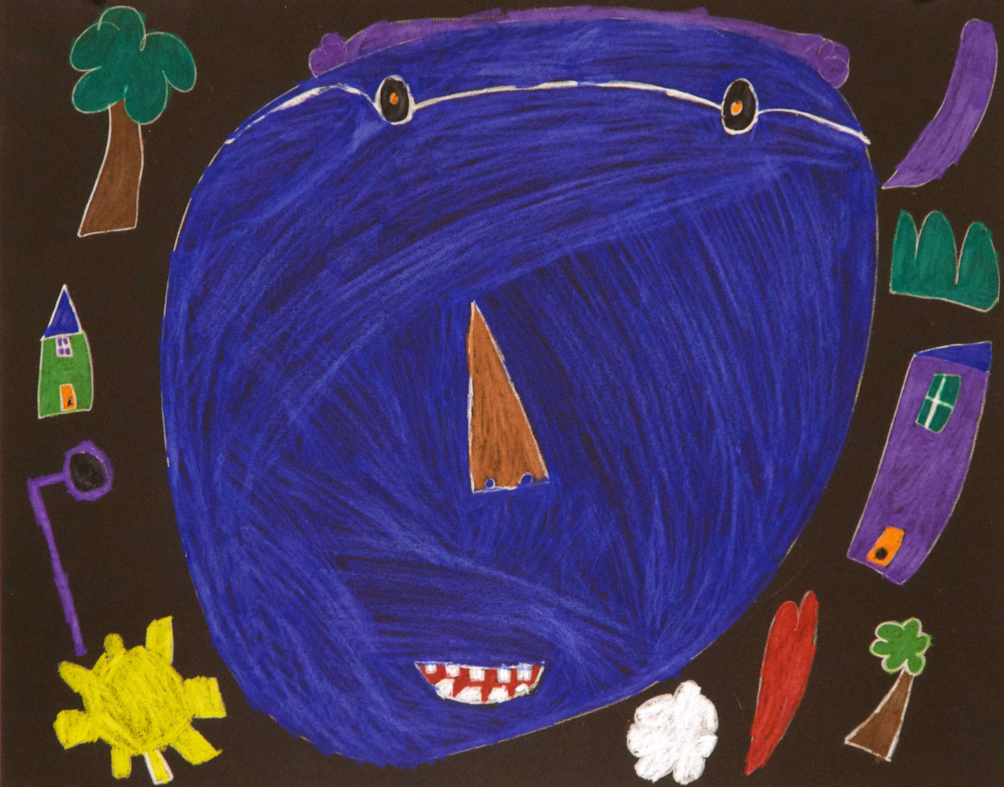 A drawing on dark paper features a large blue face at the center with a brown triangular nose, smiling mouth with teeth, black and orange eyes wearing glasses, and a small tuft of purple hair. Surrounding the face are various drawings such as a tree, a house, the sun, a heart, and a cloud.