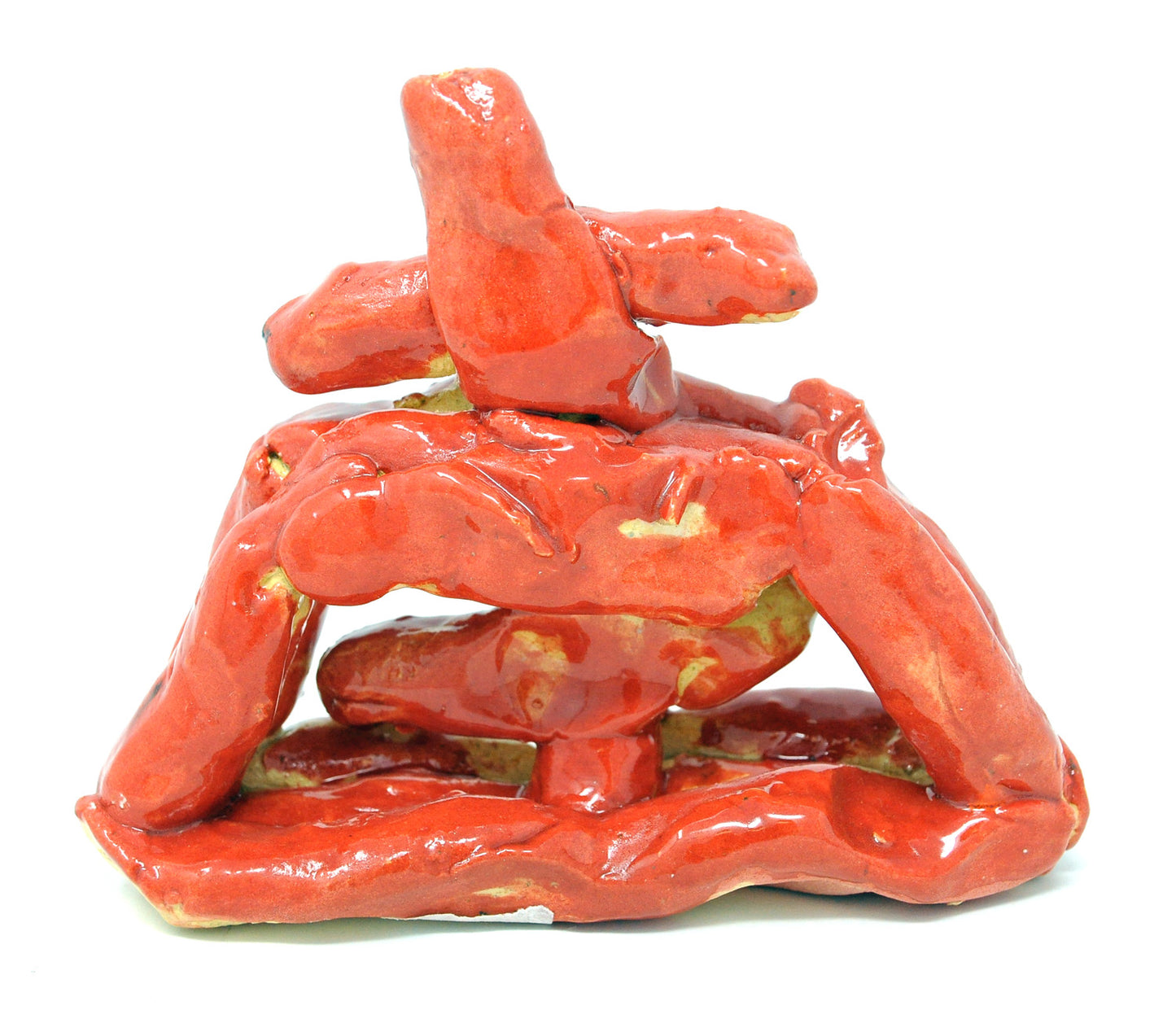 A red ceramic sculpture made of segments of rolled clay that resemble a type of structure, with a red cross on top that has a slight lean to the left, against a white background.