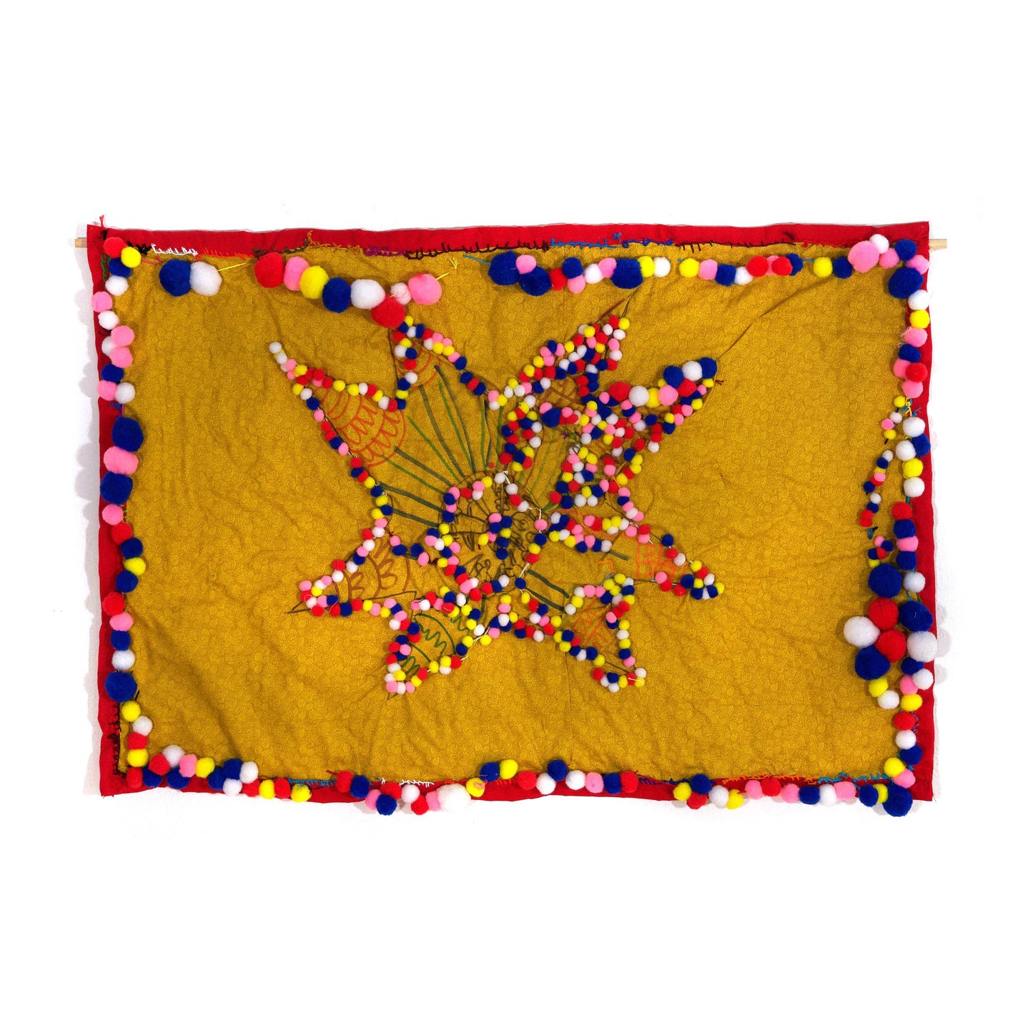 a photo of a textile artwork. A square piece of yellow fabric has a red fabric border. Tiny round pompoms in multiple colors are sewn around the border. there is a flower shape drawn in the center of the fabric with more pompom balls sewn onto its petals.