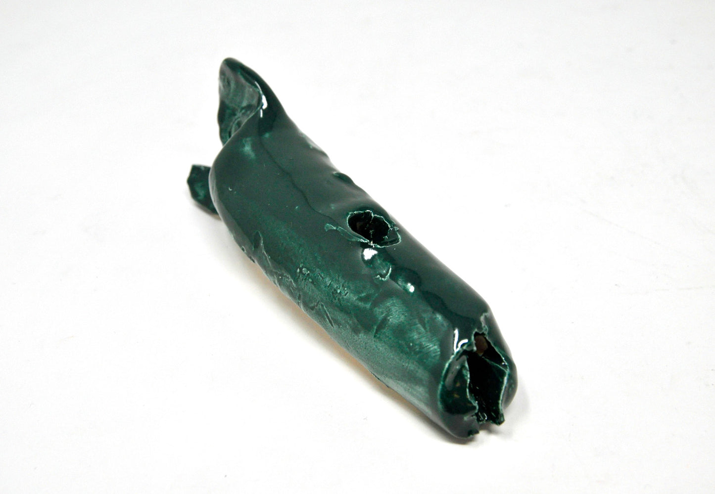 A forest green, glazed ceramic whale featuring a hole at the top.