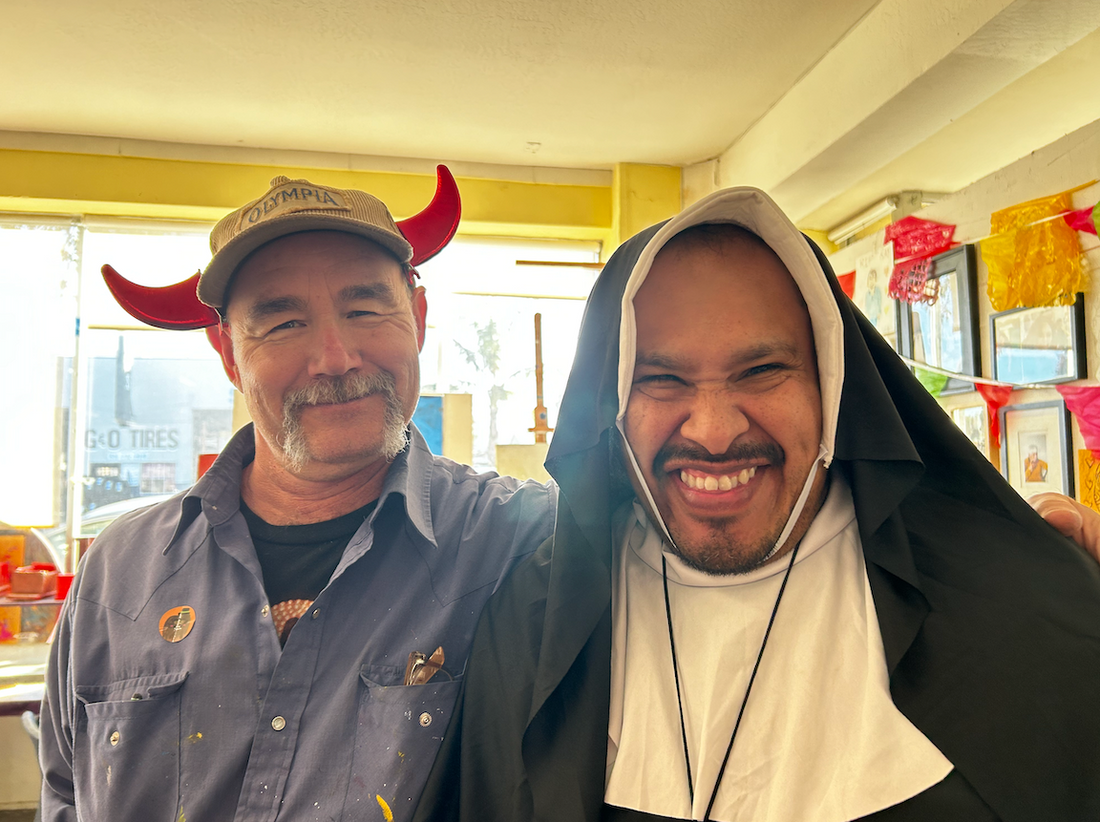 Two people, one wearing devil horns and the other wearing a nun's costume, smile for the camera.