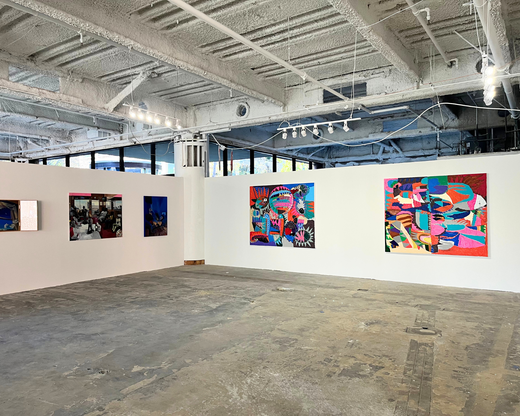 an installation shot of a large contemporary art gallery with slate floors, unfinished ceilings, and large abstract canvases