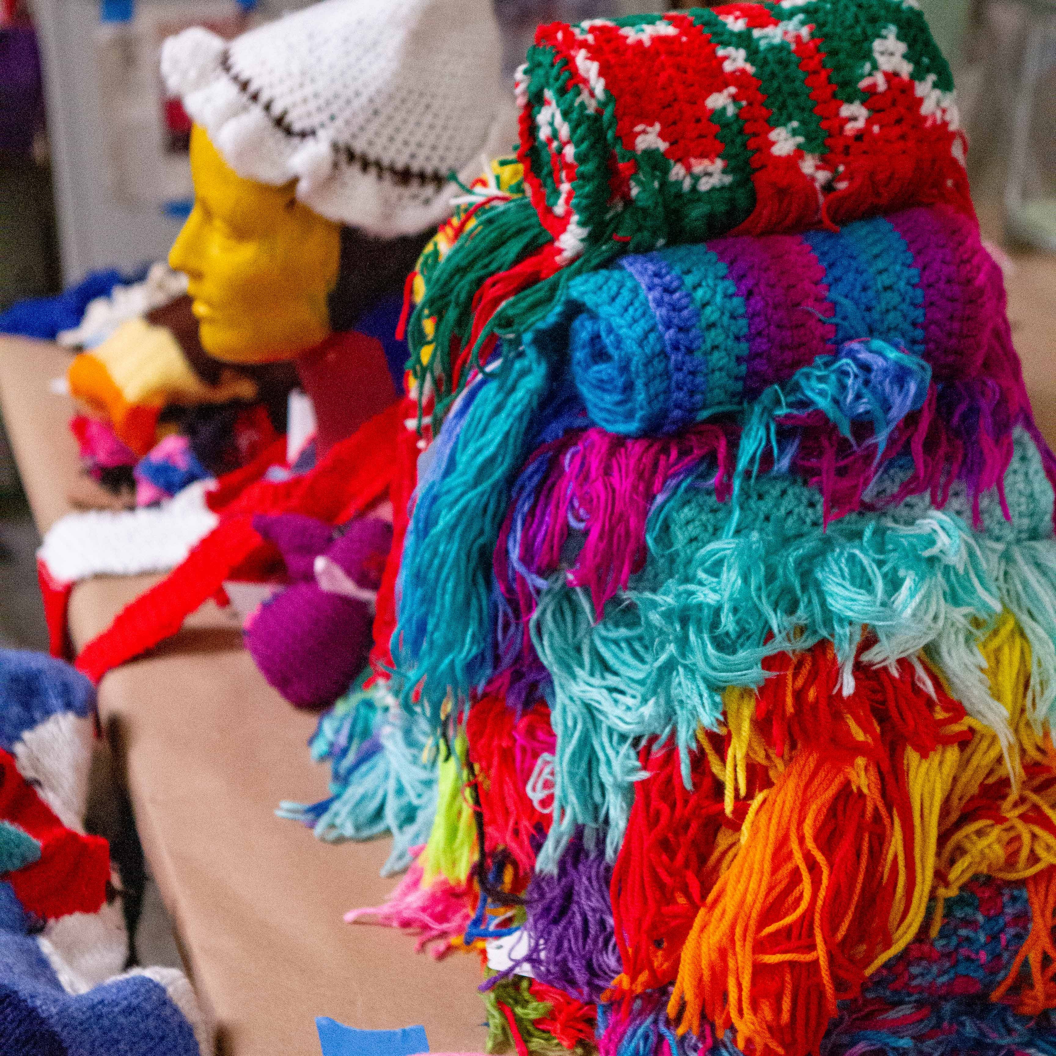 a stack of colorful afghan blankets and other crotched treasures arrayed on a table.