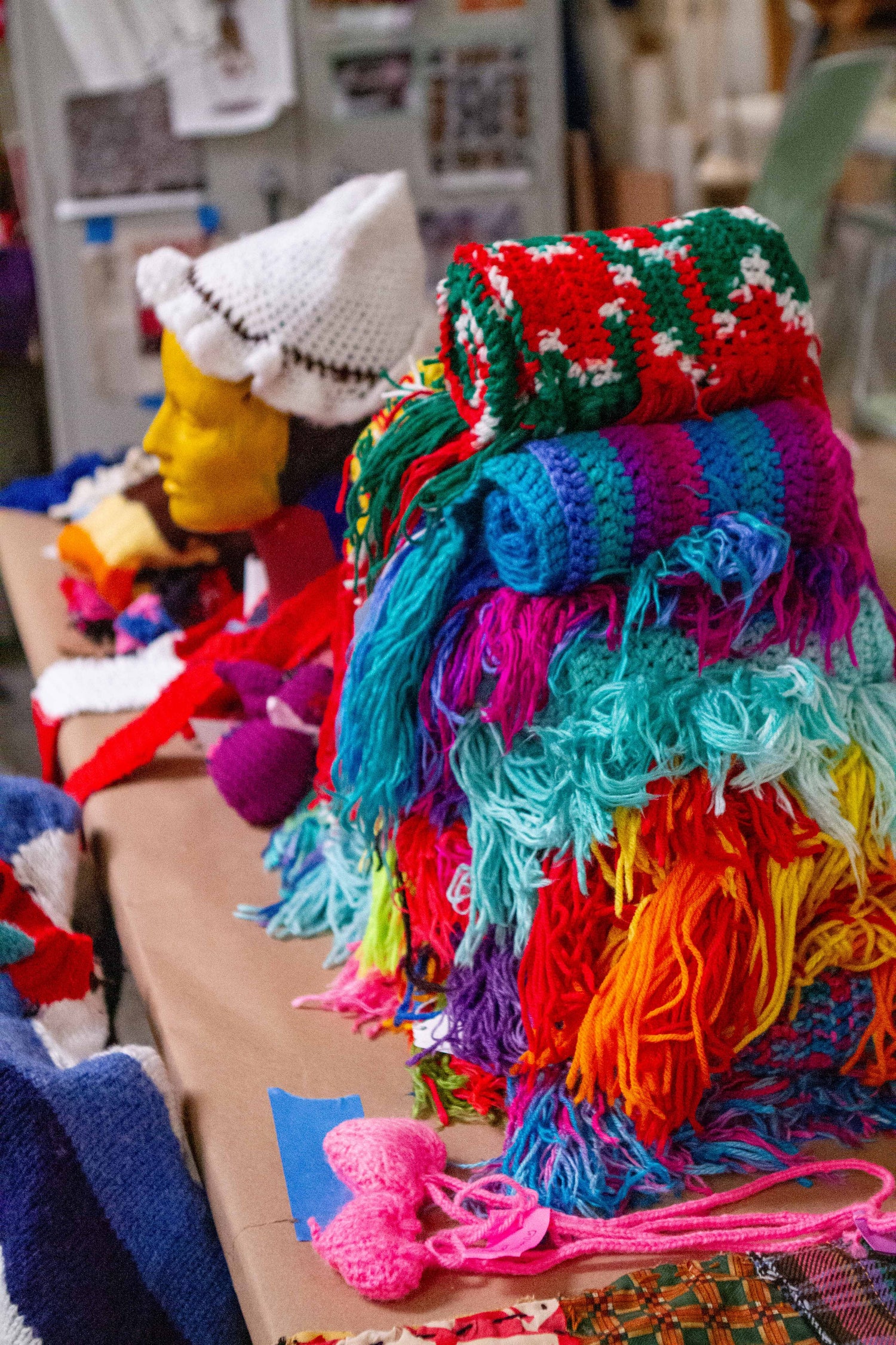 a stack of colorful afghan blankets and other crotched treasures arrayed on a table.