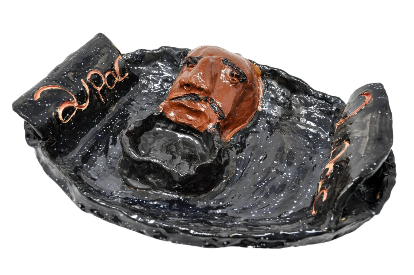 The same sculpture photographed from above. Here, the portrait head is more in focus. The bowl form, which is painted black to match the base of the platter, seems to form the exaggerated singing mouth of the central portrait head.