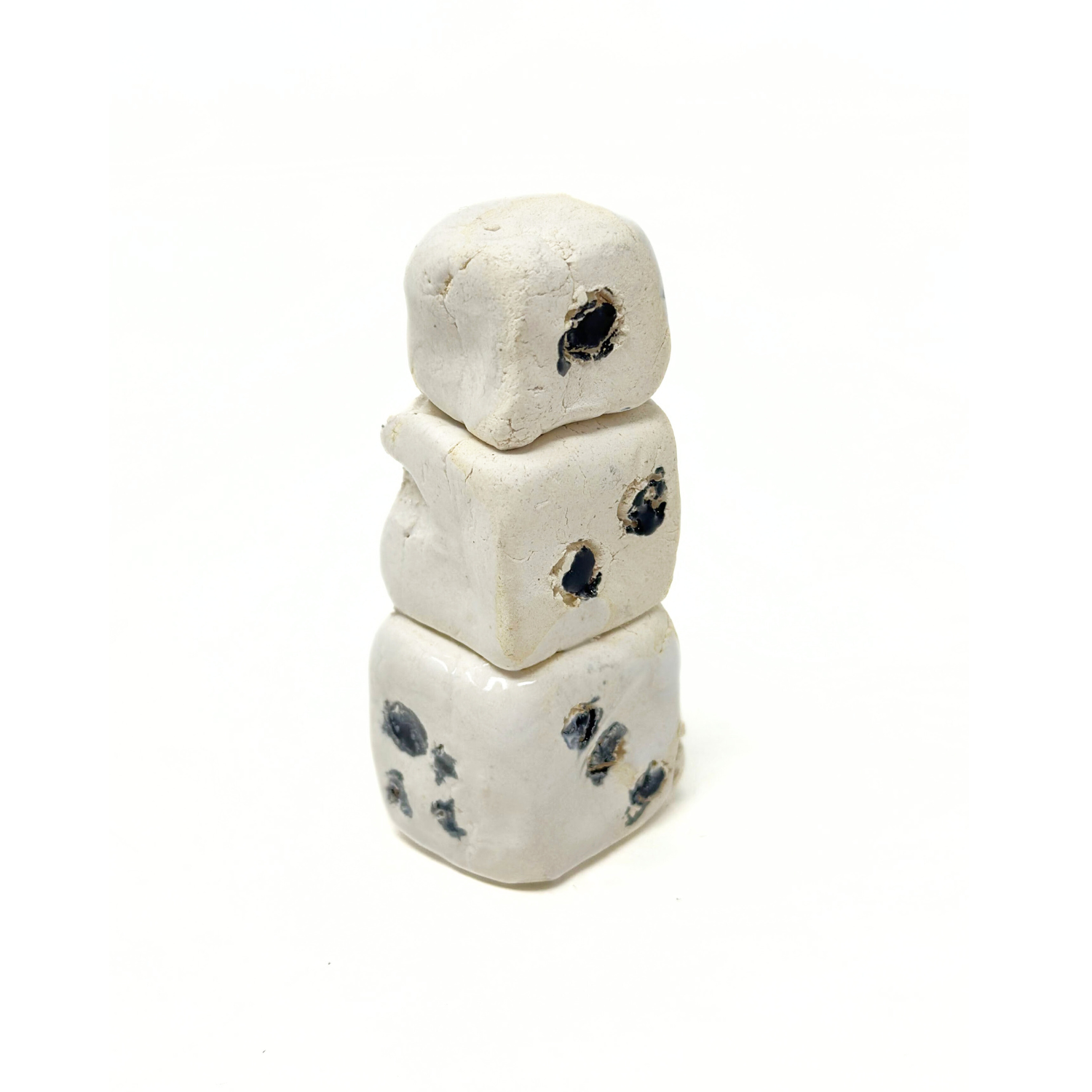 The same object photographed from another angle. Here, two sides of each die are in view. The top die has only one black dot etched on its right side, the middle die has 2 dots etched on its right side, and the bottom die has 4 dots etched on the left and 3 etched on the right. 