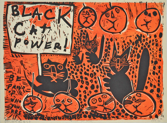 A large linoleum block print on tan paper. The image features 4 black cats and 7 jack-o-lantern pumpkins with cat faces. One of the black cats holds a picket sign that reads in all caps: "Black cat power!" The words "Be proud of who you are" are printed in the bottom left corner. The background is bright orange with a black dot pattern carved throughout.