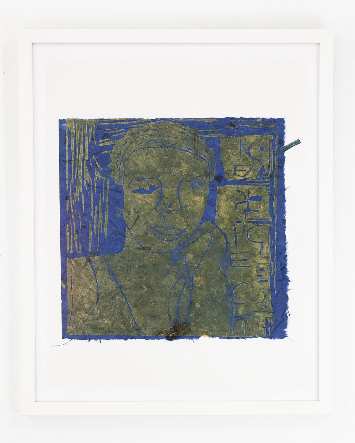 A linocut print made with green ink on handmade blue paper square. The image is a portrait: the head and shoulders of a smiling figure. There is a stack of squares behind the figure containing symbols and letters. The print is floating in a white frame and photographed on a white wall. 