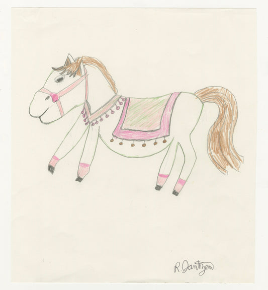 A drawing of a horse, using colored pencils on plain paper. The horse is depicted in a side profile facing left. It features a simple, rounded body with four stick-like legs. The horse is adorned with decorative elements, including a pink bridle and a blanket with a green center bordered by pink. The blanket has a series of pink and brown tassels hanging from its edges. The mane and tail are colored in light brown, contrasting with the horse's predominantly white body.