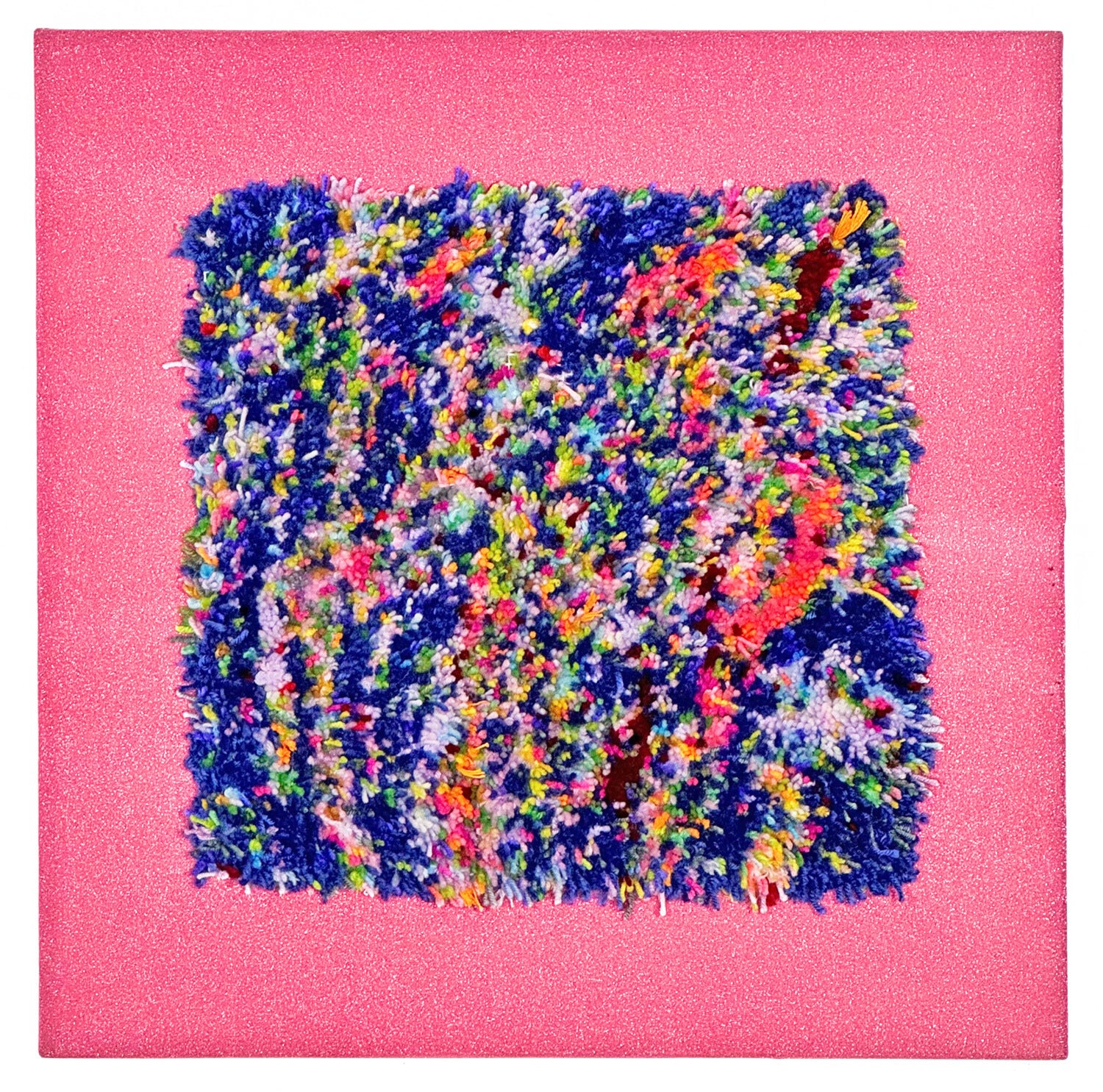A tufted rug attached to the center of a bright pink piece of fabric. The fabric has been stretched over stretcher bars so that the piece can hang like a painting on the wall. The tufted rug is a square shape made of short pieces of yarn. The surface features an abstract striped field of blue, white, and pink, with small flecks of every color of the rainbow peppered around the surface. 