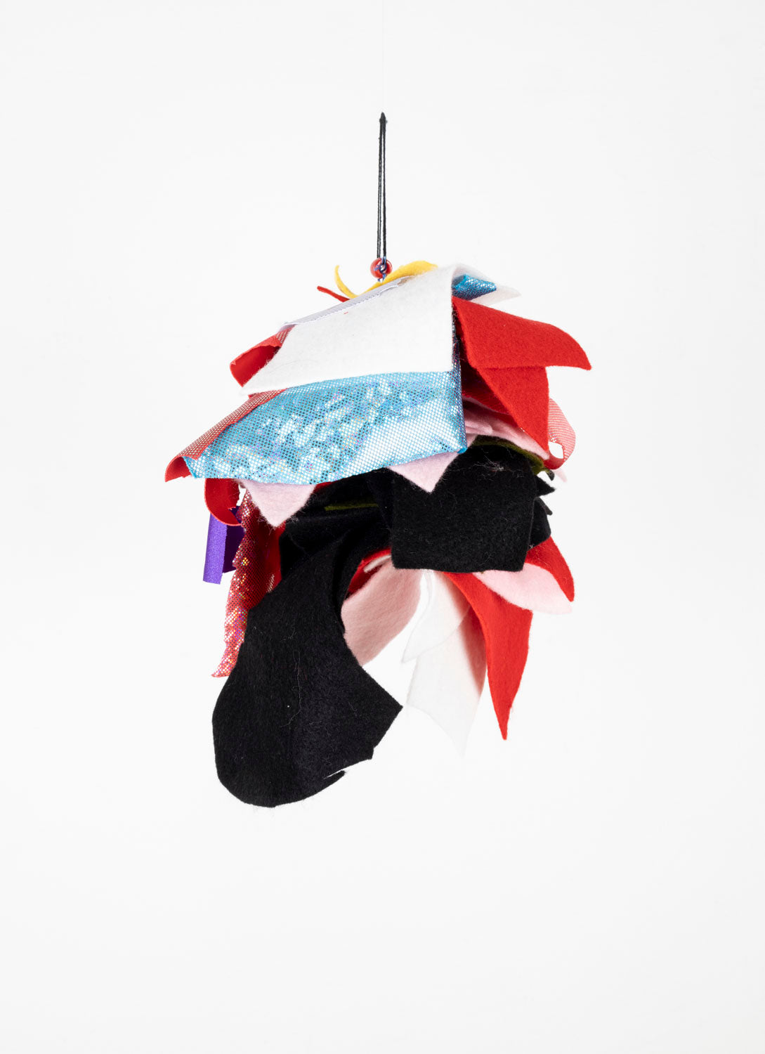 This fiber sculpture contains patches from different fabrics, arranged and sewn together. It is predominantly white, blue, red and black.
