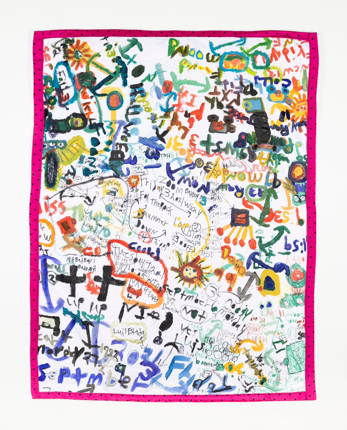 This fiber piece has a collage-like quality, with the combination of text and icons overlapping one another to form the composition of the piece. The text and icons are multi-colored; black, green, red, blue and yellow that contrast the white background. The piece is bordered with a pink and black polka dot fabric. 