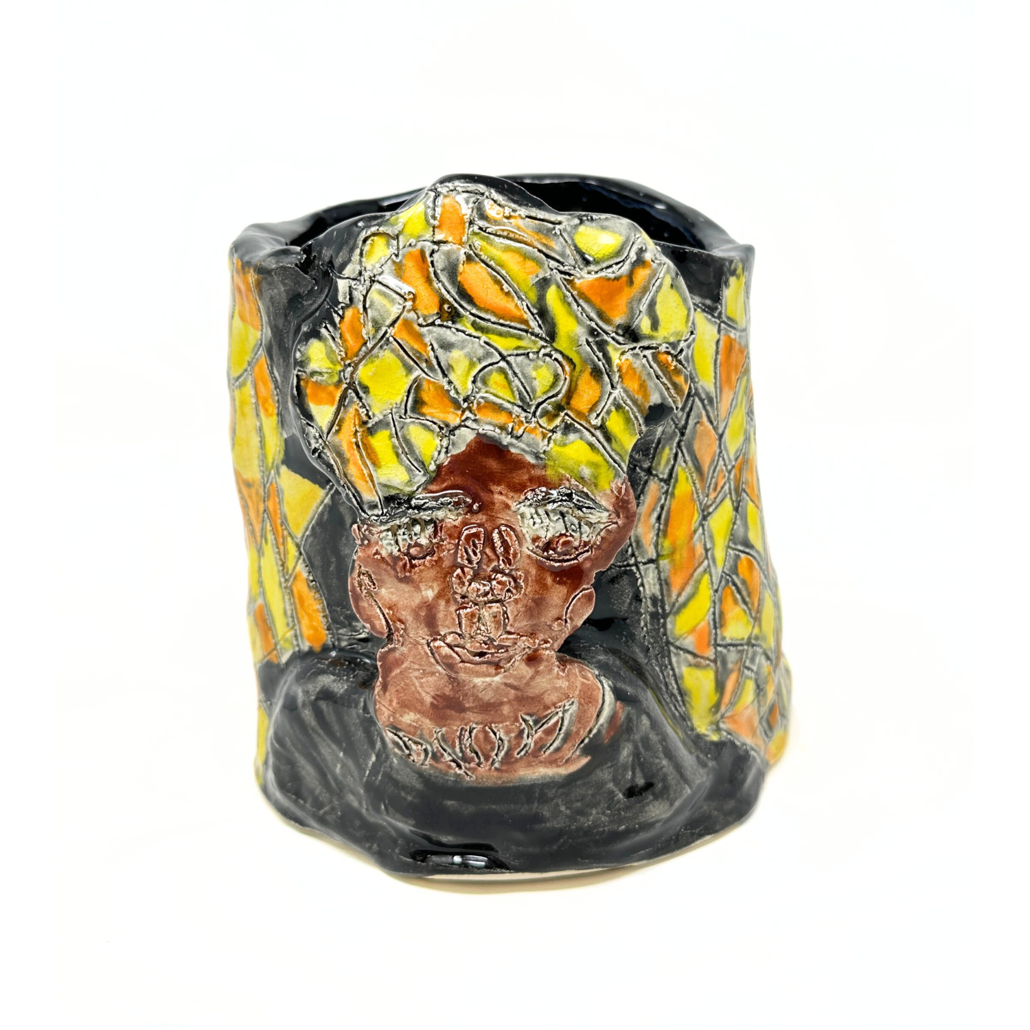 a small ceramic vessel with portraits and patterns etched across its surface. This side of the vessel shows a portrait representing an African queen:  a person with brown skin and an elaborate yellow and orange head-wrap crown. The space around the head is glazed a shinny black color. 