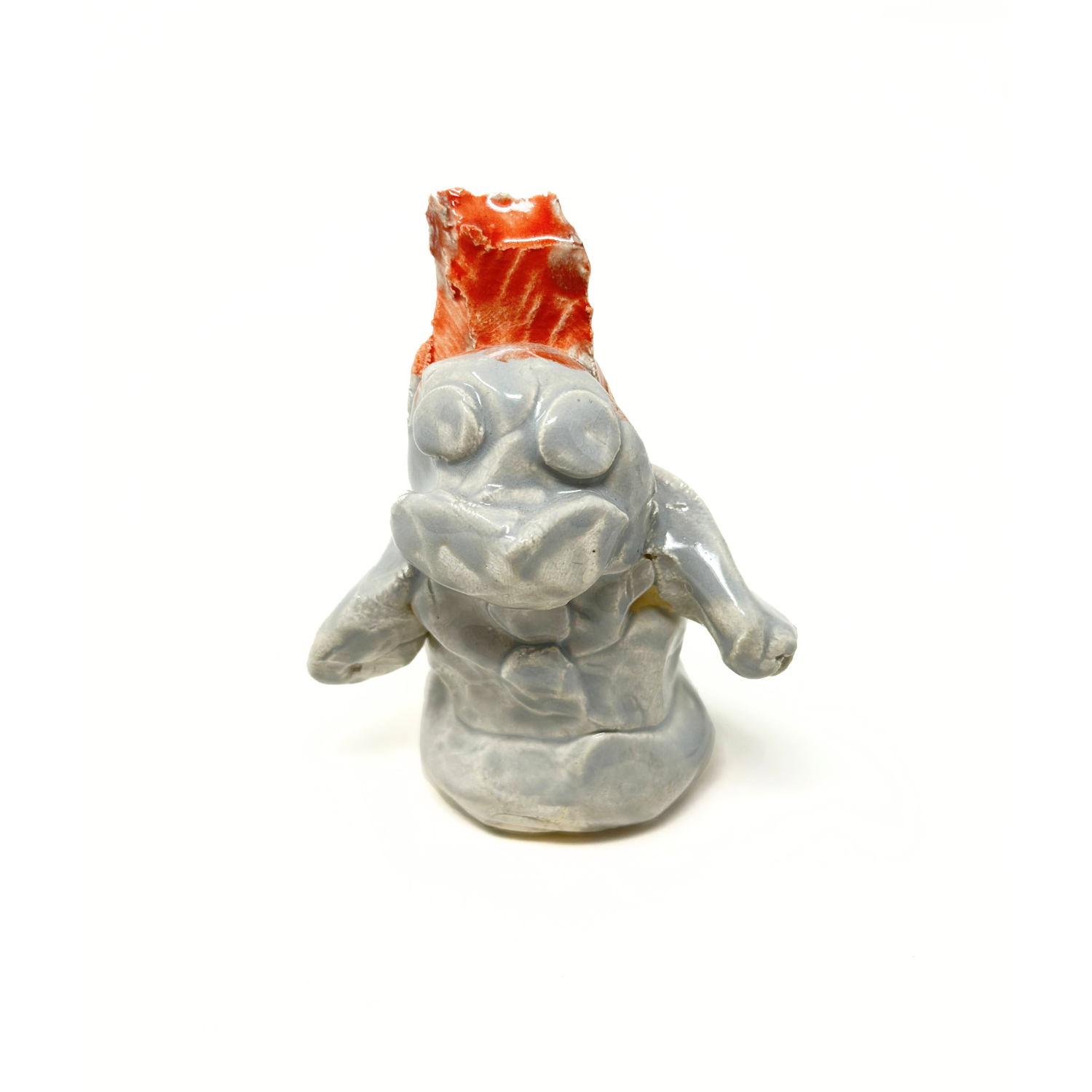 A small ceramic figurine shaped like a snowman with a red hat. The snowman is glazed a wintry grey color and made up of 3 round balls, stacked on top of one another. The head of the snowman has 2 round eyes and a smiling mouth. There are several round buttons arranged on the snowman's torso. 