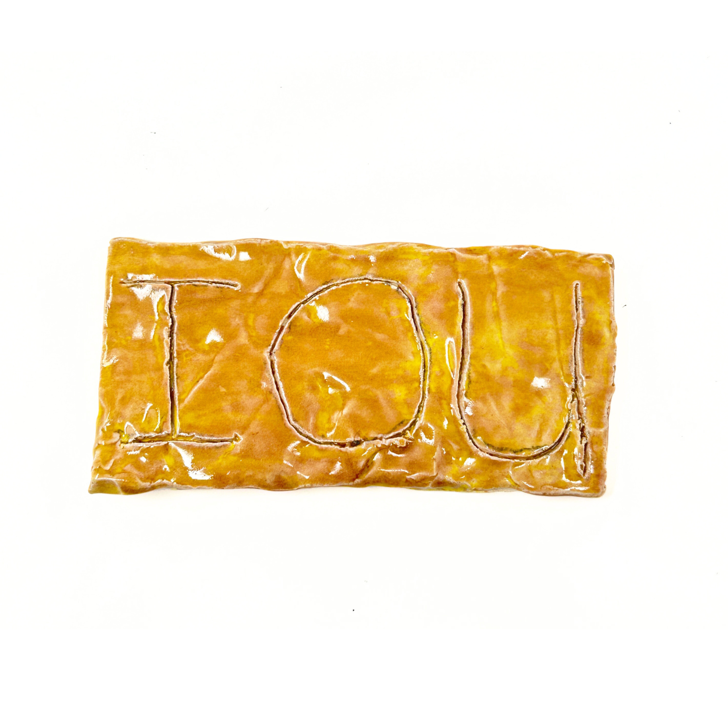 A thin rectangular ceramic plaque glazed glossy orange. Three large letters  "I O U" are etched into the surface. These reference the phonetic acronym for the words "I Owe You" as in I owe you money or services. 