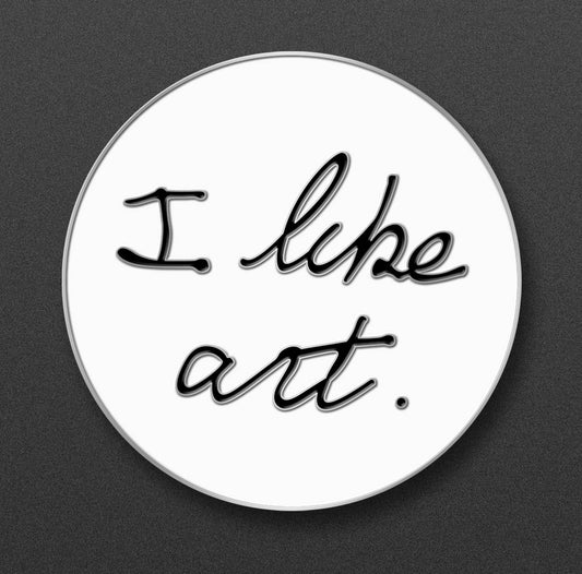 Circular enamel pin with 'I like art.' text on a white background.