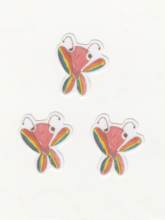 Three butterfly stickers arranged in a pyramid against a white background. The butterflies are smiling and have rainbow wings.