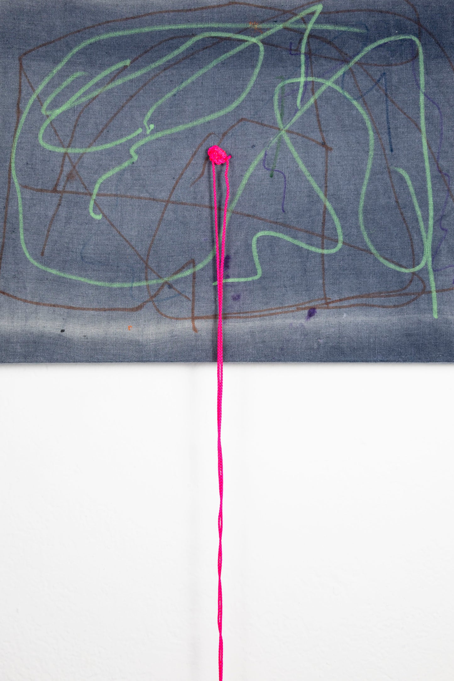  A rectangle artwork on stretched gray fabric that has been sun bleached. There are green and burgundy acrylic marker squiggle lines throughout. In the middle of the artwork, a neon pink string hadsbeen knotted and strung through, and hangs loose a few inches below the artwork.