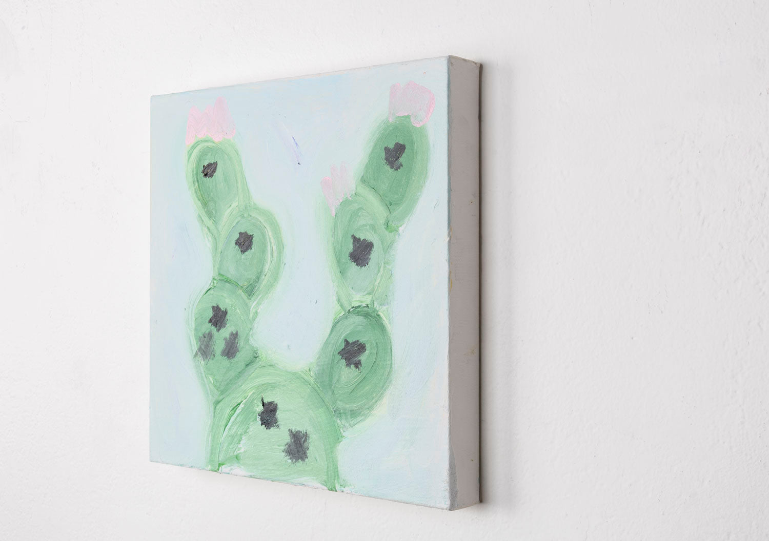 This is a painting of a cactus plant. The cactus is a muted green color, with the spiky details in black and a light pink, all against a light blue background.