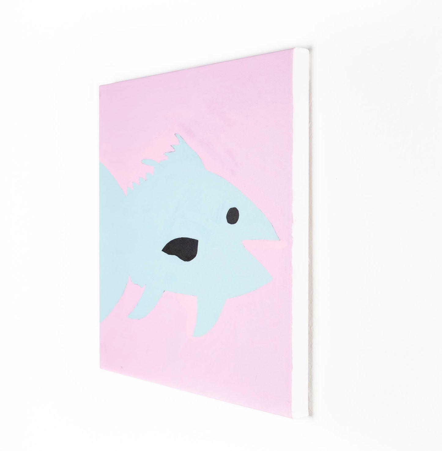 A stylized painting of a blue fin tuna against a soft pink background. The fish has a simple black eye and dark mouth, with angular fins and a streamlined body rendered in flat pastel tones. The composition is bold and playful.