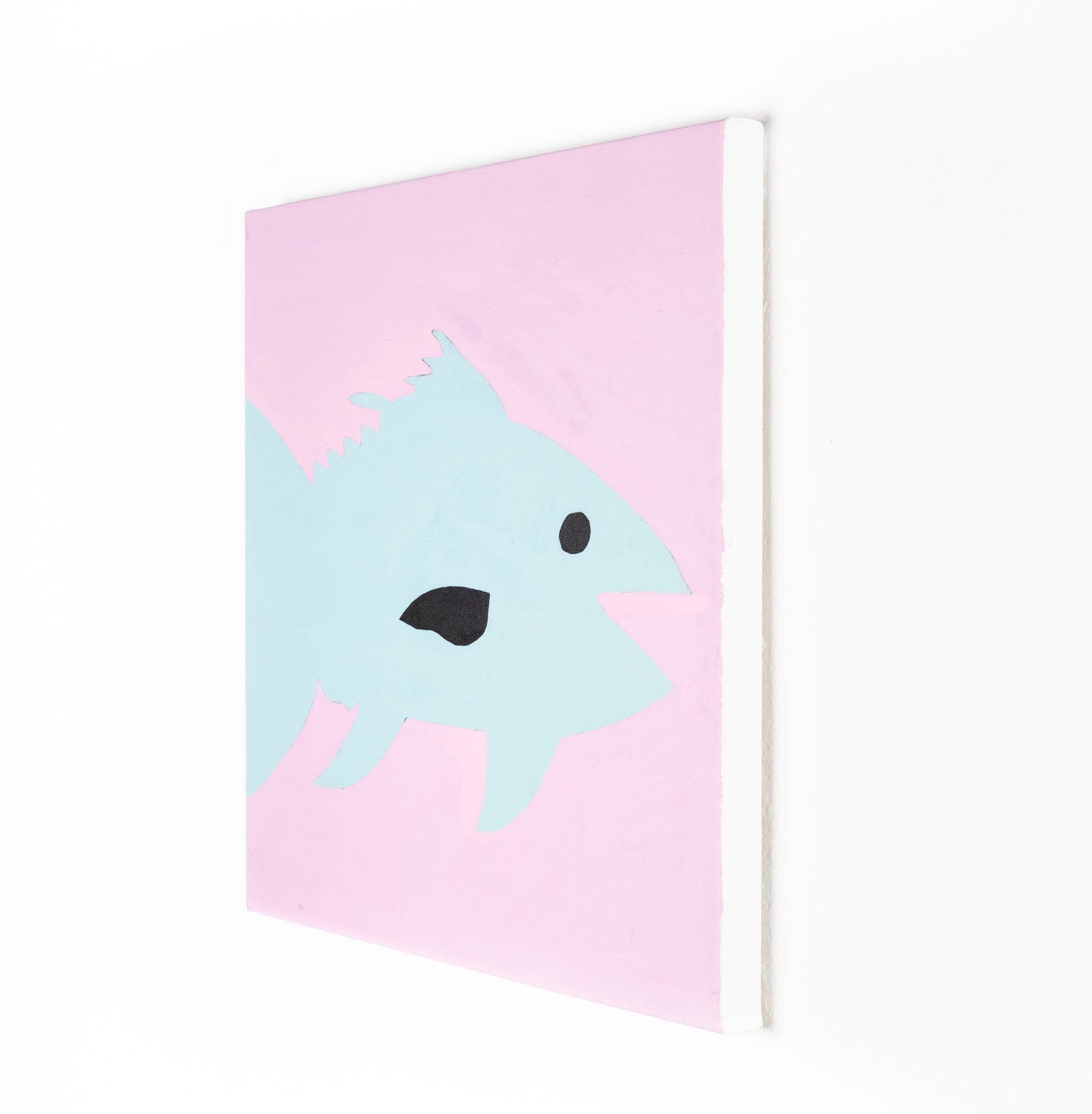 A stylized painting of a blue fin tuna against a soft pink background. The fish has a simple black eye and dark mouth, with angular fins and a streamlined body rendered in flat pastel tones. The composition is bold and playful.