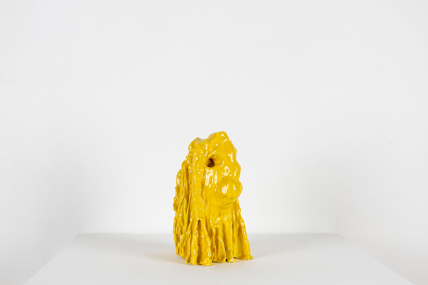 Yellow ceramic sculpture on a white background, photographed in profile