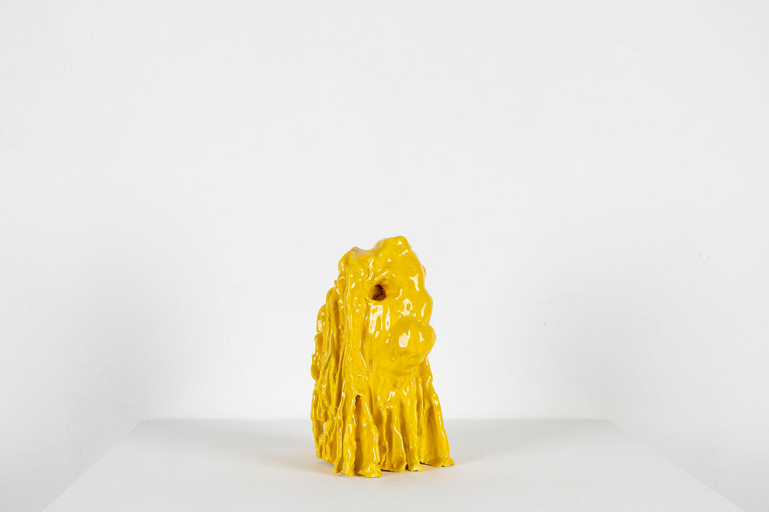 Yellow ceramic sculpture on a white background, photographed in profile