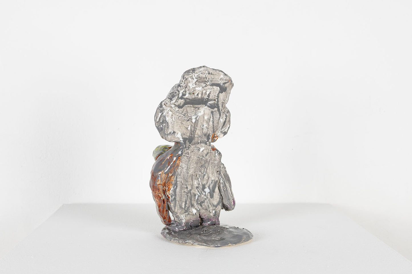 The same figurative sculpture photographed from the back. This side of the sculpture is glazed all grey. 