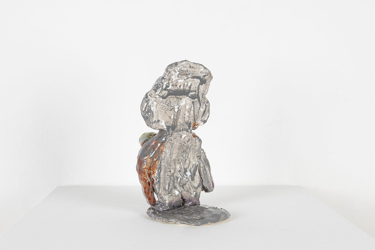 The same figurative sculpture photographed from the back. This side of the sculpture is glazed all grey. 