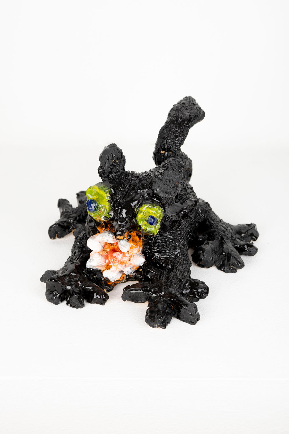 Black ceramic cat figurine with colorful eyes against a white background.