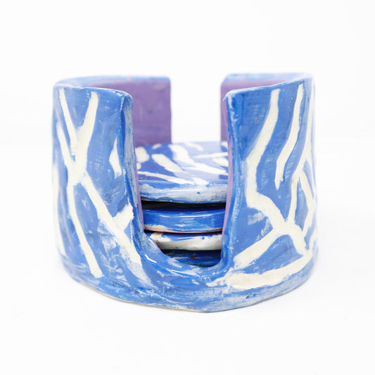 A ceramic coaster set with a blue and white abstract design, against a white background.