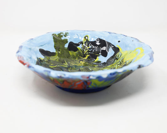 A ceramic bowl covered in a predominantly light blue glaze on the inside and a darker blue on the outside. On top of the blue base there is a marbling effect created with green, yellow, red and black glaze.