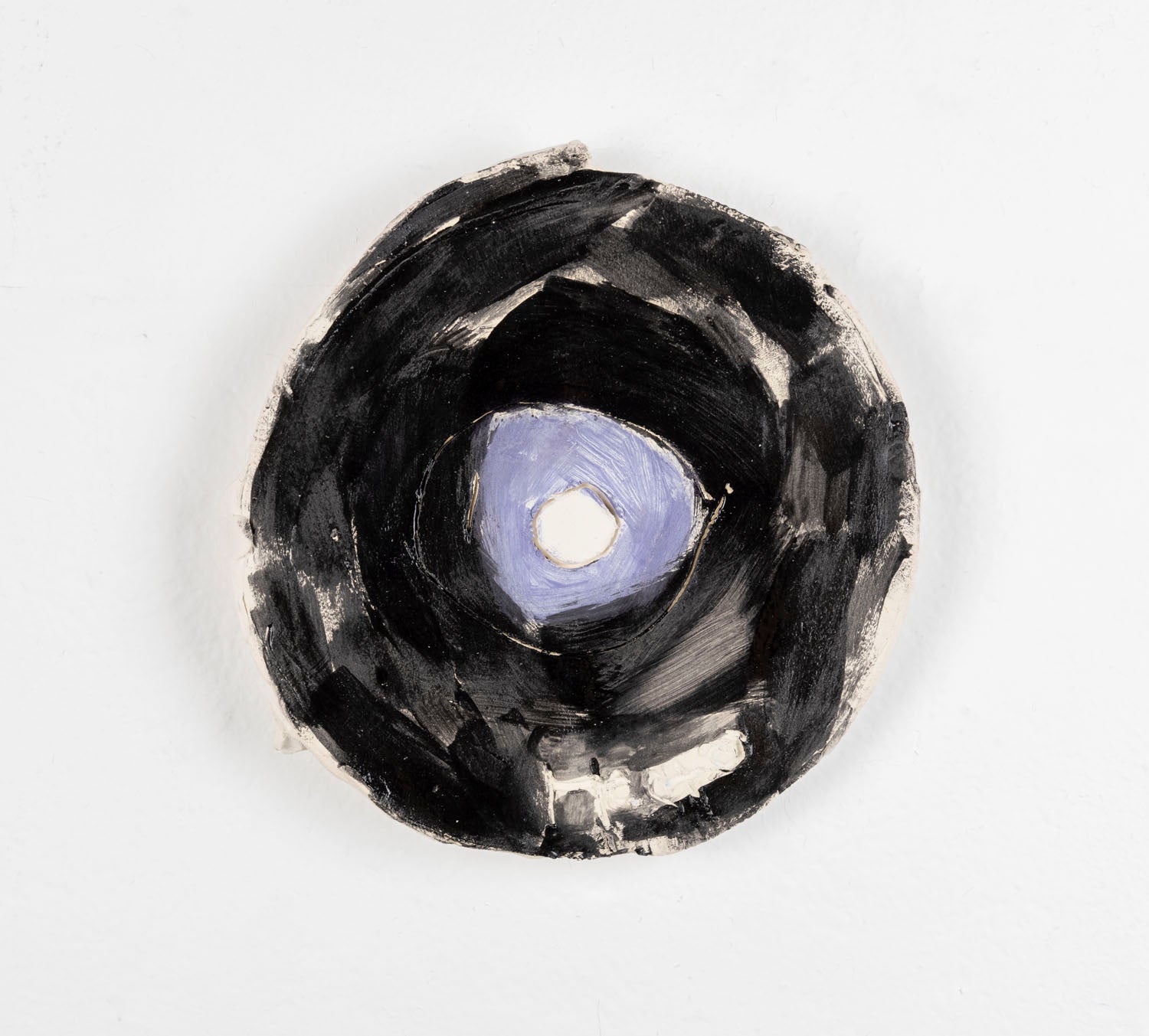 This is a ceramic sculpture of a record, the majority of the record is glazed in black, with a purple glaze for the center.