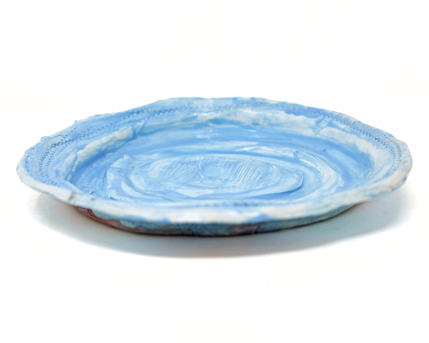 This ceramic plate is glazed light blue. There are carved details along the edges of the plate, and in the center. 