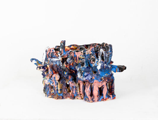 a ceramic sculpture of a two-tiered, cage-like structure glazed in shiny blue and matte pink. The structure is made of little cylinders, some are stacked vertically, others are wrapped around the form in horizontal bands, and several radiate out around the perimeter. There are gaps between each cylinder through which the white background is visible.