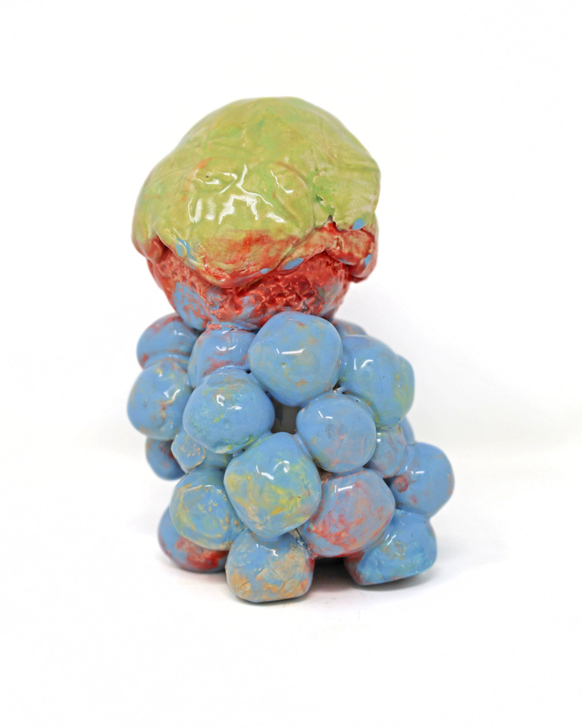 This ceramic sculpture contains one larger sphere stacked on top of many smaller spheres. The smaller spheres are connected and glazed together with a light blue glaze, with hints of red. The larger sphere on top is also attached, with the bottom half of the sphere that same red and the top half a lime green. 