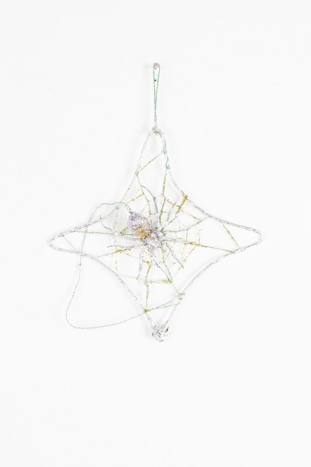 This mixed media sculpture is of a spider and its web. It is gold and silver, with hints of purple. There is a luminescent quality to the work, with the spider and the web blending into each other. 