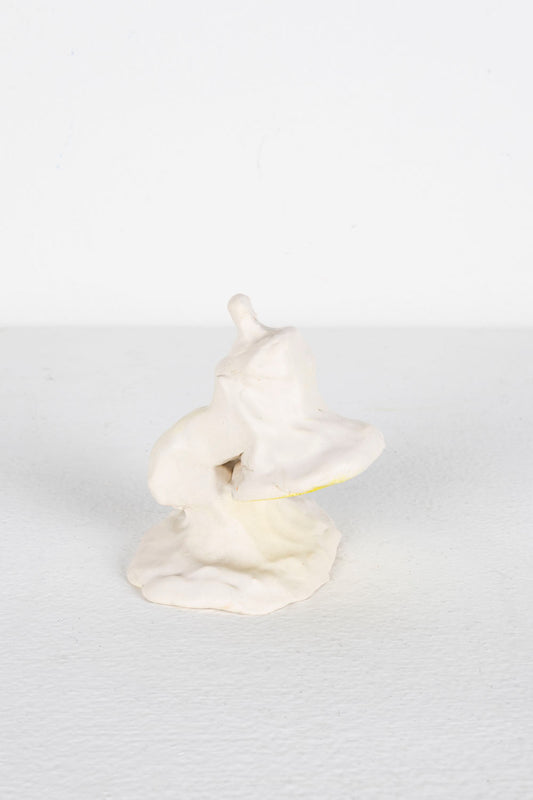 This is a ceramic piece depicting a Mini Luxo. It is glazed predominantly in white, with yellow highlights. 