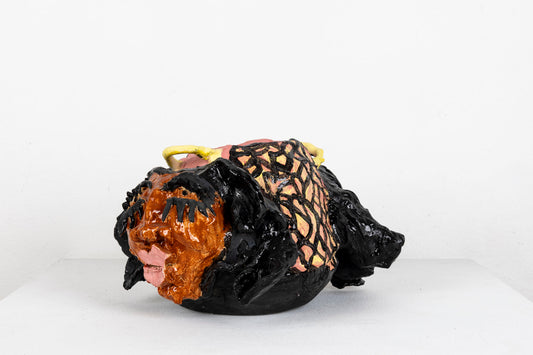 This sculpture is an abstracted figure, their facial features carved out, with pink glaze for the lips and black glaze for the eyelashes and hair.