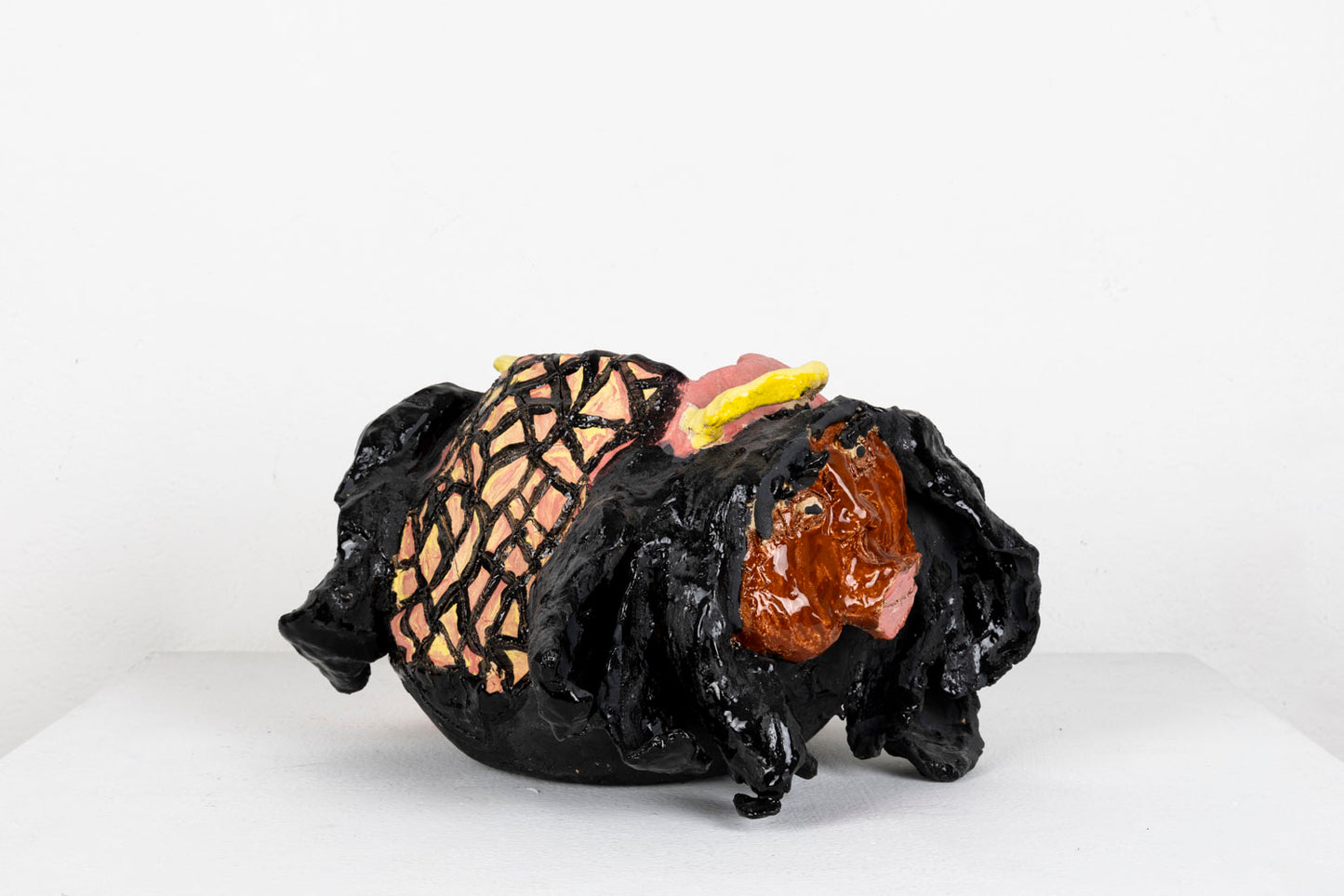 This sculpture is an abstracted figure, their facial features carved out, with pink glaze for the lips and black glaze for the eyelashes and hair.
