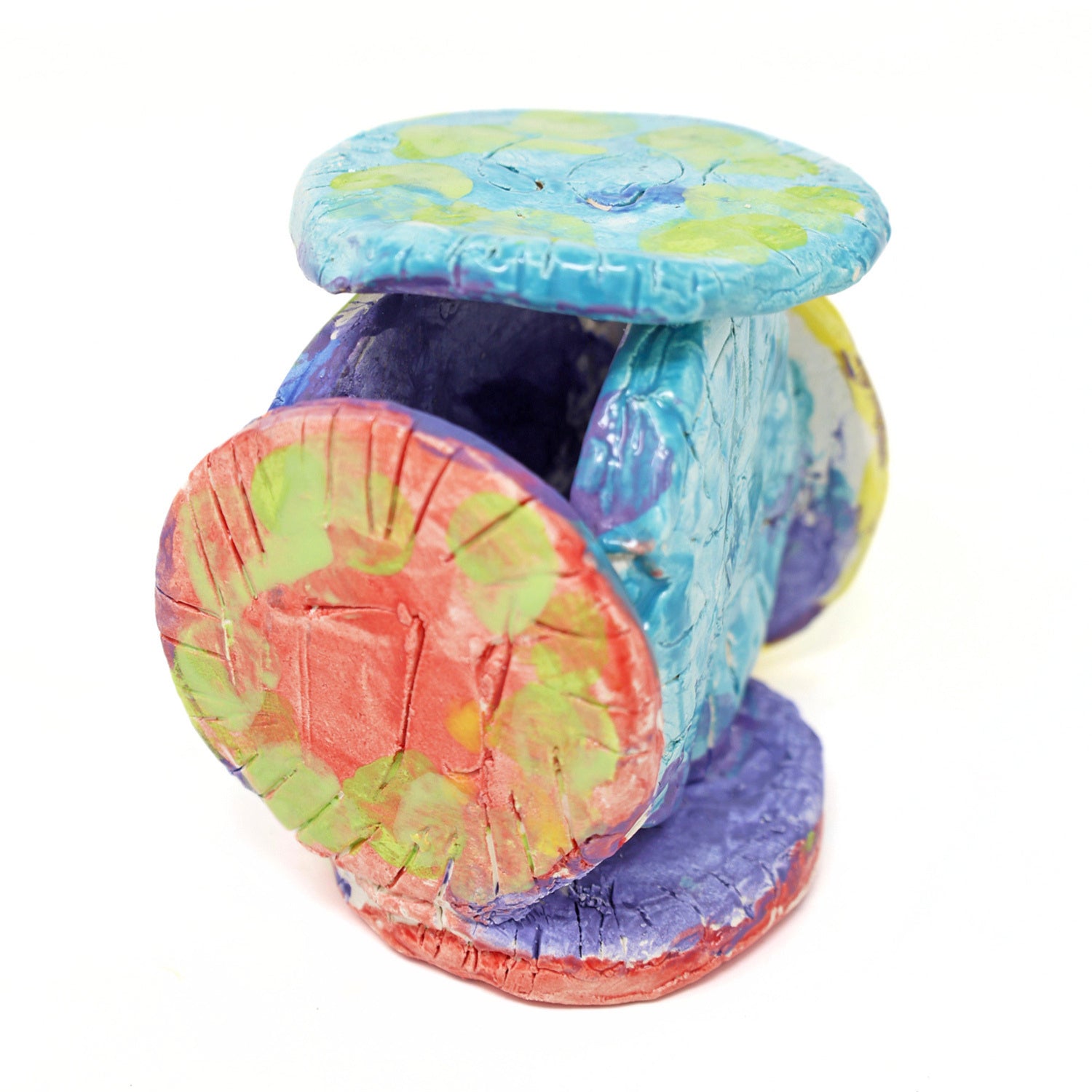 The ceramic sculpture contains 6 circles that are all connected. The piece is glazed with vibrant colors, including varying shades of green, red, blue, purple and yellow. There are also carved details on the face of each circle.