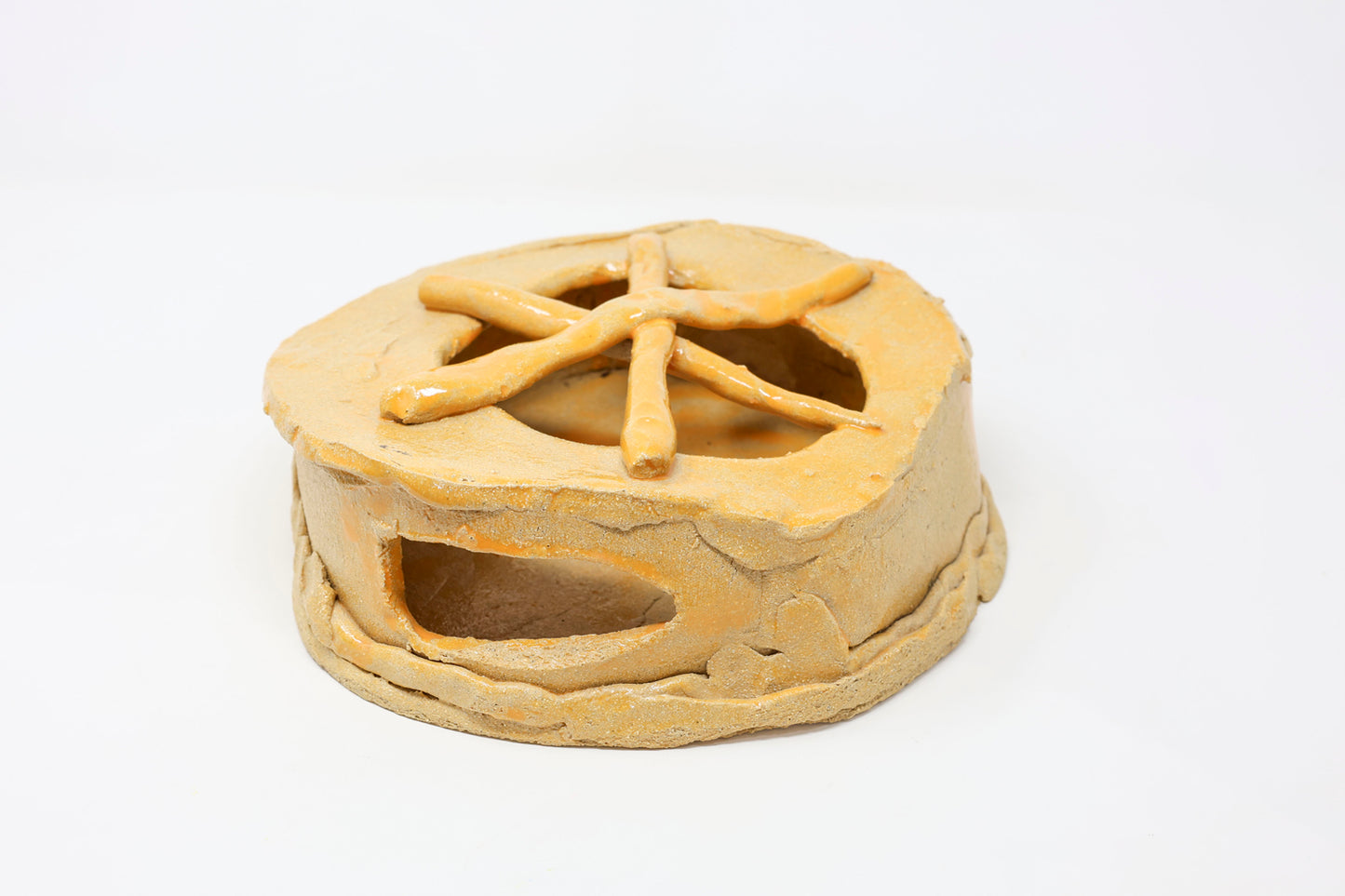 Yellow hollow ceramic sculpture with a naturalistic design. It is a cylindrical vessel with an opening at the front and partial openings at the top.